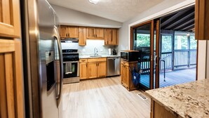 A kitchen with wooden cabinets, stainless steel appliances, and a view to an outdoor deck. - Gorgeous 3-bedroom house with 2nd living rooms in charming Roswell (Roswell)