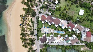 Vue aérienne d’un complexe hôtelier comprenant plusieurs bâtiments, une piscine et une plage.
