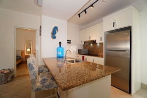 A modern kitchen with granite countertops, stainless steel appliances, and white cabinetry. - Beach Paradise: 2-bedroom condo in delightful Las Terrenas with AC (Las Terrenas)