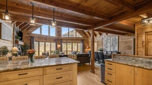 Una cocina amplia con armarios de madera, encimera de mármol y ventanas grandes.