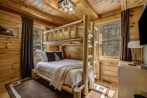 A wooden cabin bedroom with a bunk bed, a desk, and a window with a view of trees. - Private Retreat w/ Views, Hot Tub + Game Room (Lenoir)