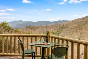 A wooden deck with a table and chairs overlooking a mountainous landscape. - Private Retreat w/ Views, Hot Tub + Game Room (Lenoir)