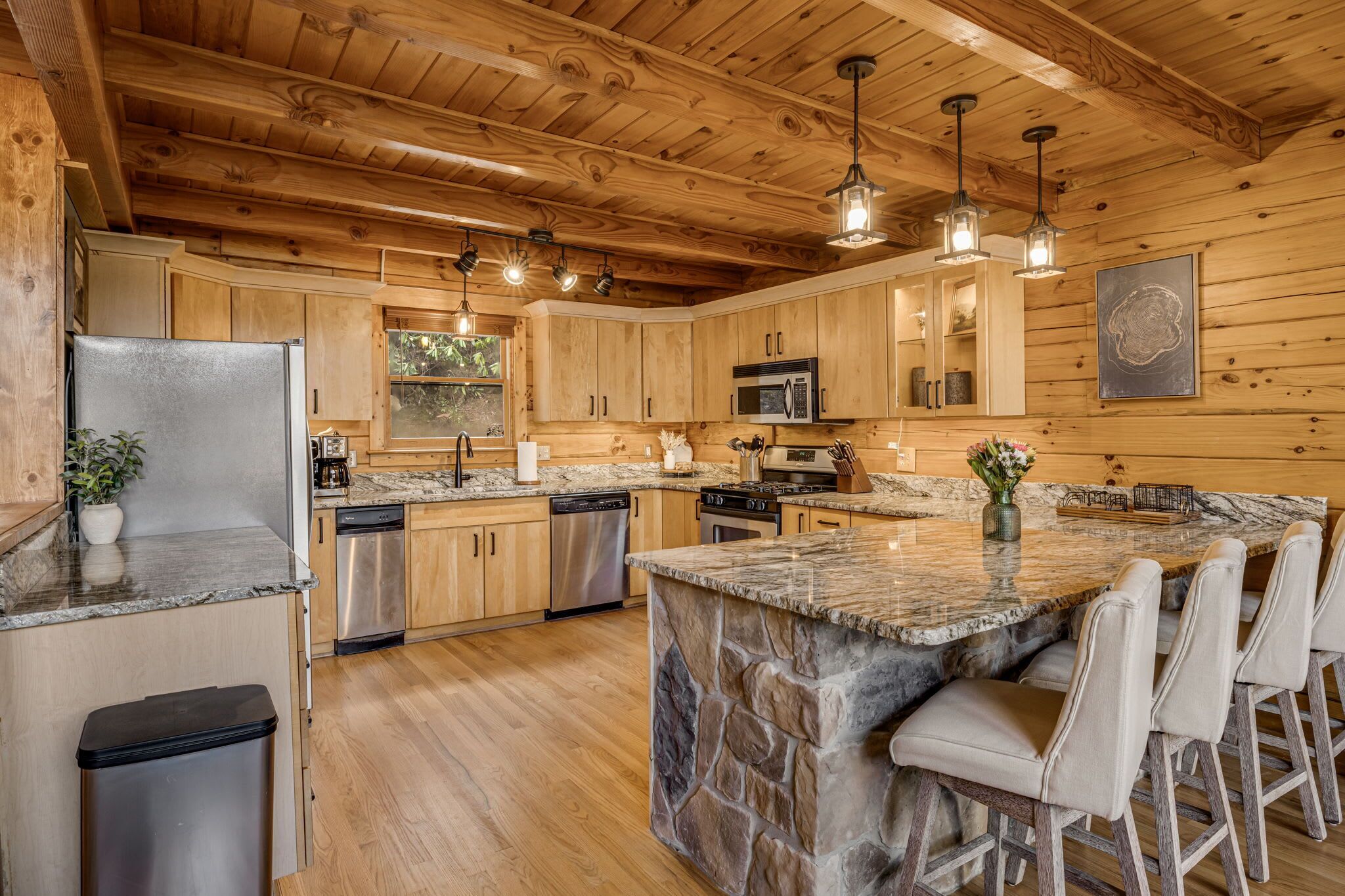 A kitchen with wooden cabinets, granite countertops, a central island with bar stools, and a stone backsplash.