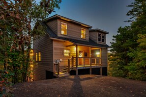 A two-story wooden house with a porch, a staircase, and a garage. - 4 Bed Cabin great for multi generational families - Heated Indoor Pool & Games (Sevierville)