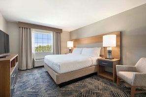 A hotel room with a large bed, two bedside lamps, a TV, a chair, and a window with curtains. - Extended Stay America Annapolis, Womack Drive (Annapolis)