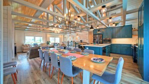 A spacious dining area with a wooden table, grey upholstered chairs, and a kitchen with teal cabinets and stainless steel appliances. - Third Sandbar & Seaglass Landing by Avantstay. Sleeps 30 2 Homes + Dual Pools + Outdoor Living Steps to Beach (Port Aransas)