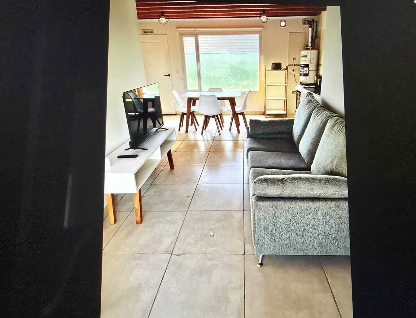 A living room with a sofa, TV, and a dining table with chairs.