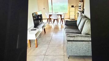 A living room with a sofa, TV, and a dining table with chairs.
