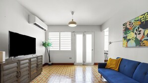 Sala de estar com televisão, sofá e piso estampado.