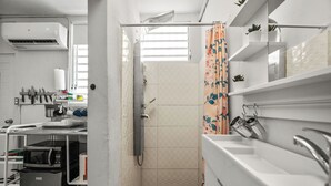 Cozinha compacta com micro-ondas, pia e prateleiras para armazenamento.