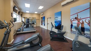 A gym with treadmills, stationary bikes, and a large poster of a beach scene. - Cozy 2-bedroom condo in adorable Orlando with AC and gym access (Orlando)