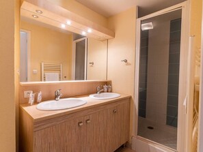 A bathroom with two sinks, a mirror, and a shower enclosure.