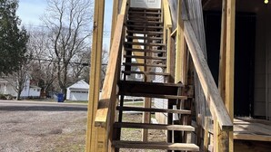 Una escalera de madera que lleva a una puerta blanca, rodeada por una estructura de madera.