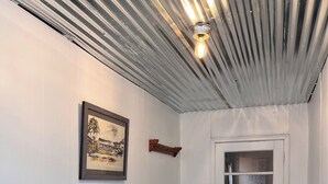 Un pasillo con un banco, una puerta con ventana y un aplique en el techo.