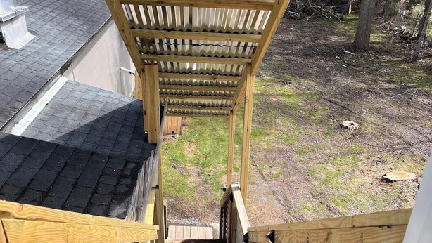 Una escalera de madera al aire libre que conduce a una zona cubierta con techo de metal.
