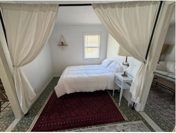 Une chambre à coucher avec un lit, une table de chevet, une lampe et des rideaux.