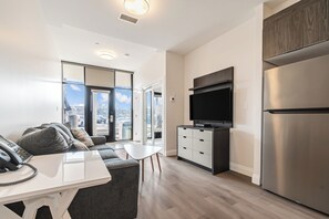 Ein modernes Apartment mit Küche, Essbereich, Wohnzimmer mit Sofa und einem großen Fenster mit Blick auf die Stadt.