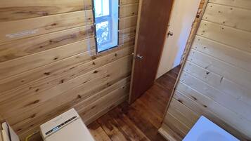 A small, wooden-paneled bathroom with a toilet, a sink, and a window.
