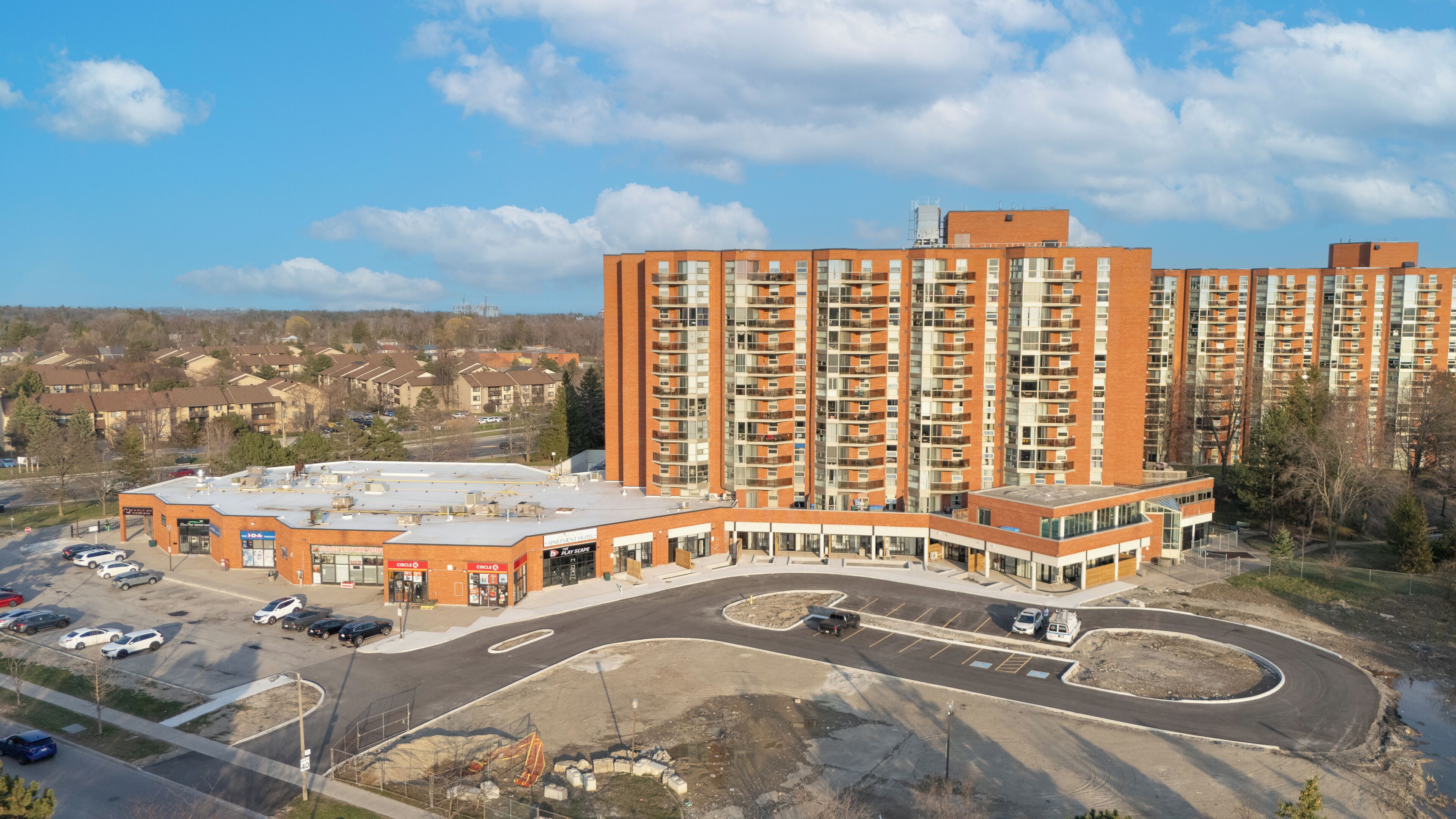 A multi-story residential building with a parking lot and a commercial building with a drive-thru.