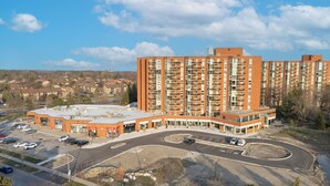 Un immeuble résidentiel à plusieurs étages, doté d’un parking et d’un bâtiment commercial avec un service au volant.