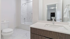 Une salle de bain moderne équipée de toilettes, d’une douche, d’un lavabo et d’un miroir.