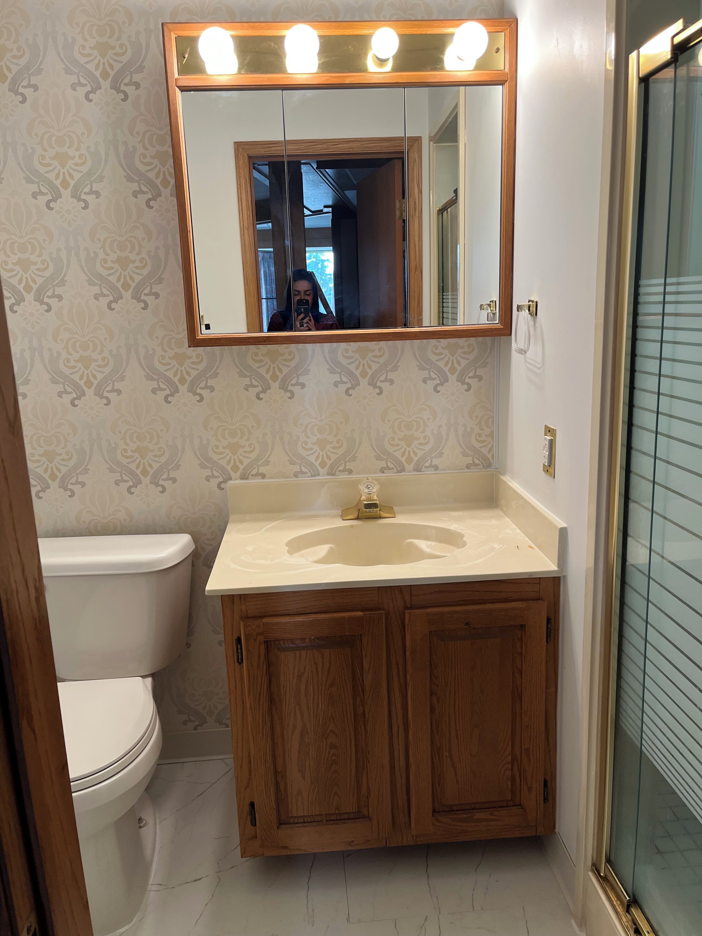 A bathroom with a vanity, a toilet, and a mirror with lights.