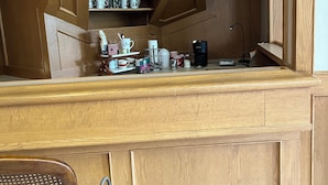 Et træ-køkken med indbygget kaffemaskine, elkedel og diverse køkkenredskaber.