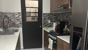 Een moderne keuken met een marmeren vloer, roestvrijstalen apparatuur en een zwarte deur.