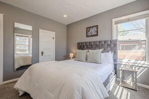 A bedroom with a large bed, a bedside table, a nightstand, a window, and a door. - NEW! Starlight Stay | Outdoor Oasis w/ Game Room! (Fruita)