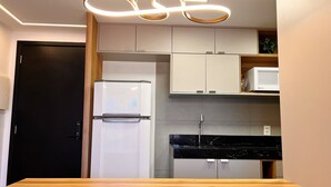 Eine moderne Küche mit Kühlschrank, Mikrowelle und schwarzem Arbeitsplatz.