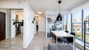 A modern kitchen with a dining area, a sofa, and a view of the city. - Downtown Luxurious 2BD|Pool |Parking|Hot Tub|Sauna (Vancouver)