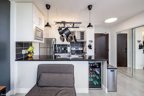 A modern kitchen with a central island, overhead lighting, and a built-in refrigerator. - Downtown Luxurious 2BD|Pool |Parking|Hot Tub|Sauna (Vancouver)