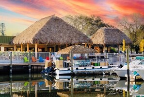 A marina with thatched-roof structures, a dock with boats, and a clear sky. - Bright Sarasota Studio, Pool + Waterfront + IMG, Minutes To Beaches (Sarasota)