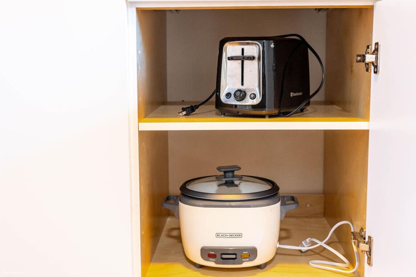 Un armario de cocina con un tostador y una olla de cocción lenta.