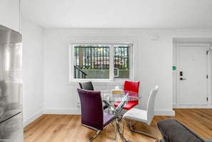 Ein moderner Essbereich mit einem Glastisch, Metallstühlen und Blick auf einen Balkon.