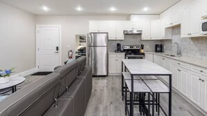 A modern kitchen with white cabinets, stainless steel appliances, a marble countertop, and a built-in bench. - Modern 2BR Retreat |Free Parking |Desk| Fast Wi-Fi (Surrey)