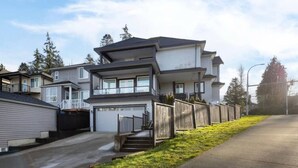 A modern multi-story residential building with a garage, a fenced yard, and a clear sky. - Modern 2BR Retreat |Free Parking |Desk| Fast Wi-Fi (Surrey)