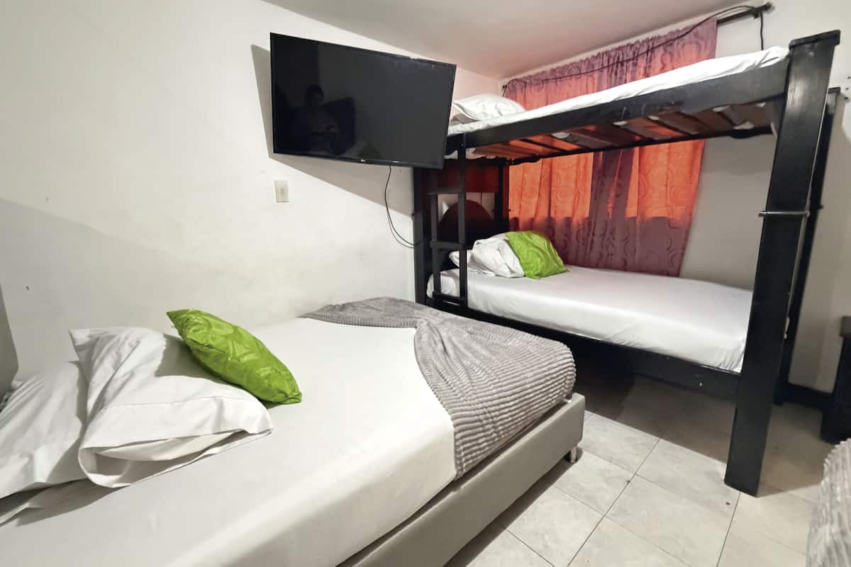 A room with two bunk beds, a television mounted on the wall, and a curtain.