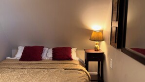 Een hotelkamer met een bed, kussens, een nachtkastje met een lamp en een aan de muur hangend schilderij.