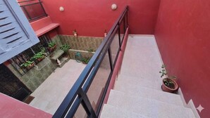 Eine Treppe mit Metallgeländer, Blumentöpfen und einer roten Wand.