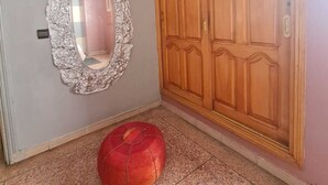 Ein Zimmer mit einem großen Holzschrank, einem Zier-Spiegel und einem roten Hocker.