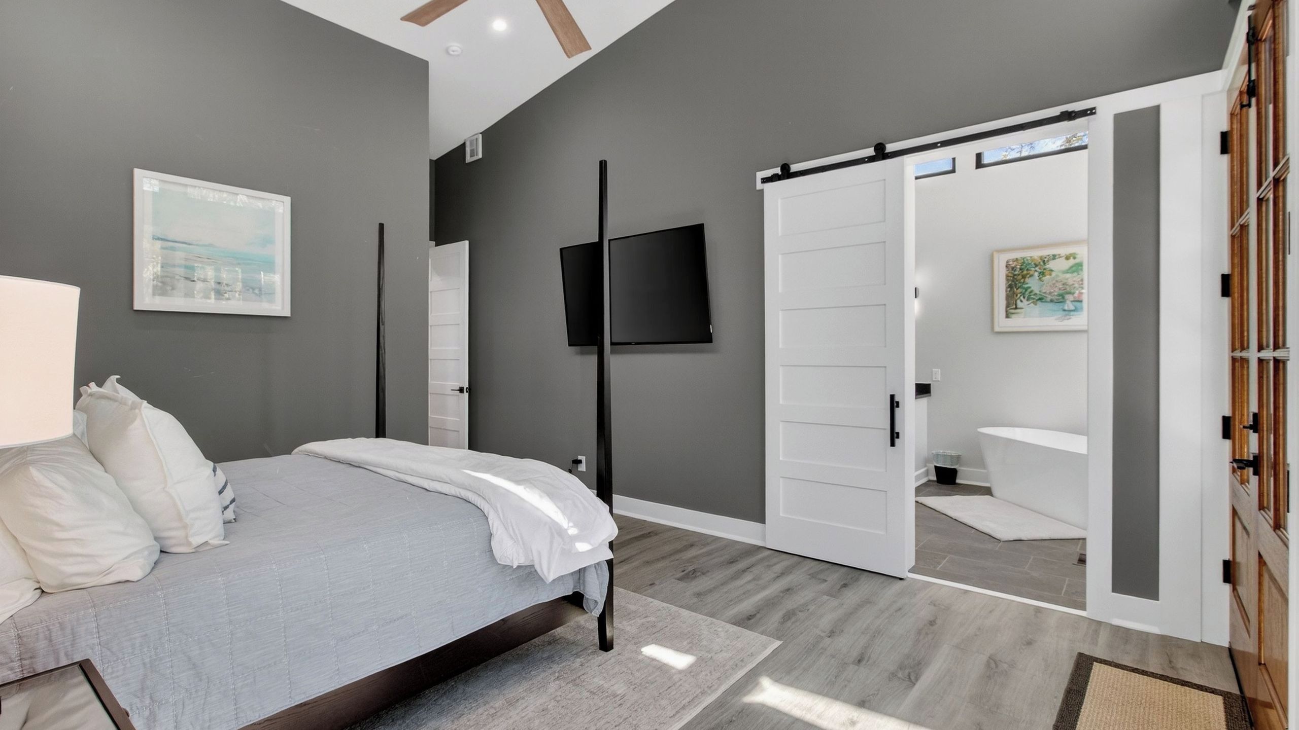 A bedroom with a bed, a TV, a wardrobe, and a bathroom visible through an open door.