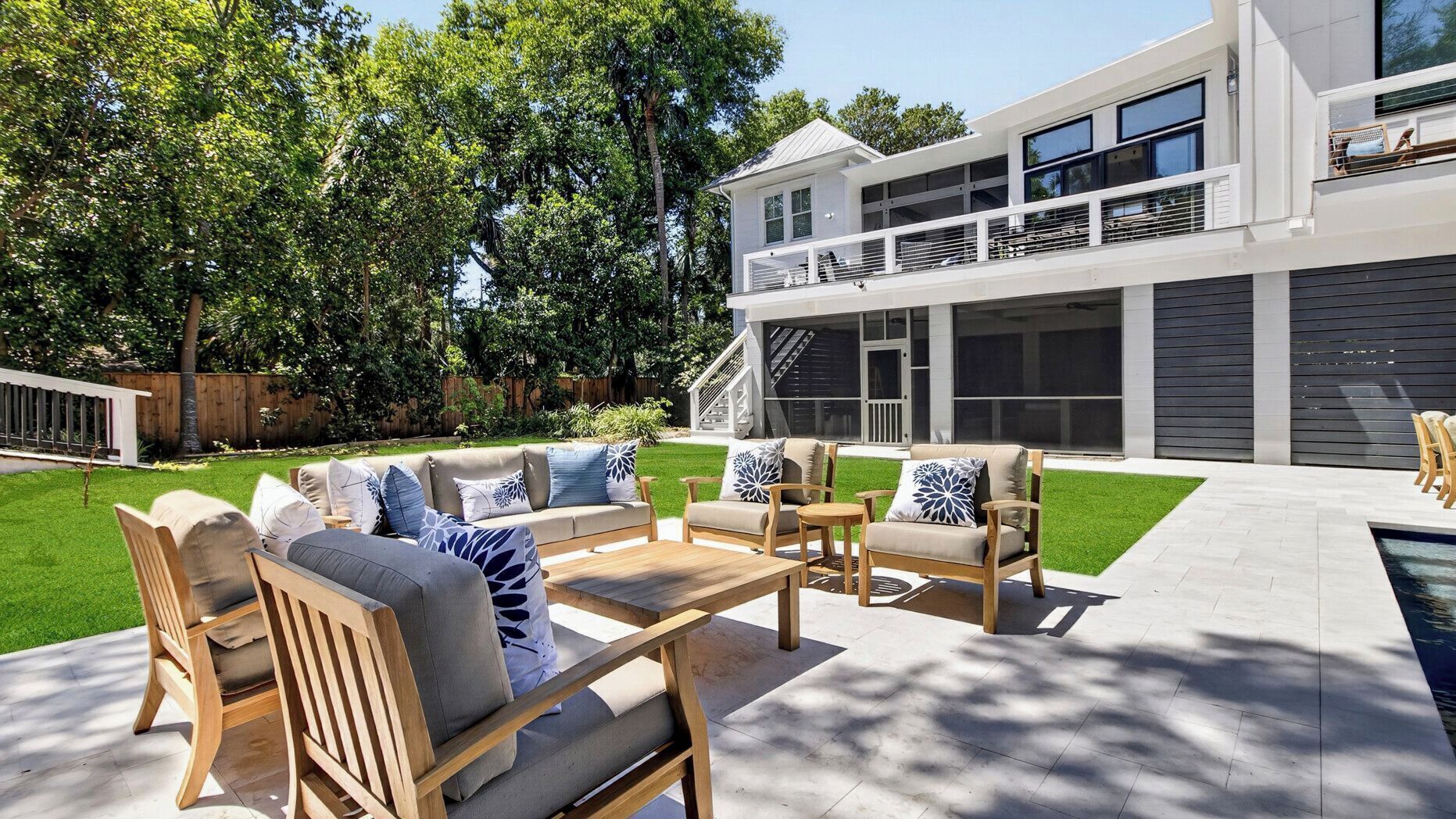 A modern house with a spacious outdoor patio, a pool, and a well-maintained lawn.