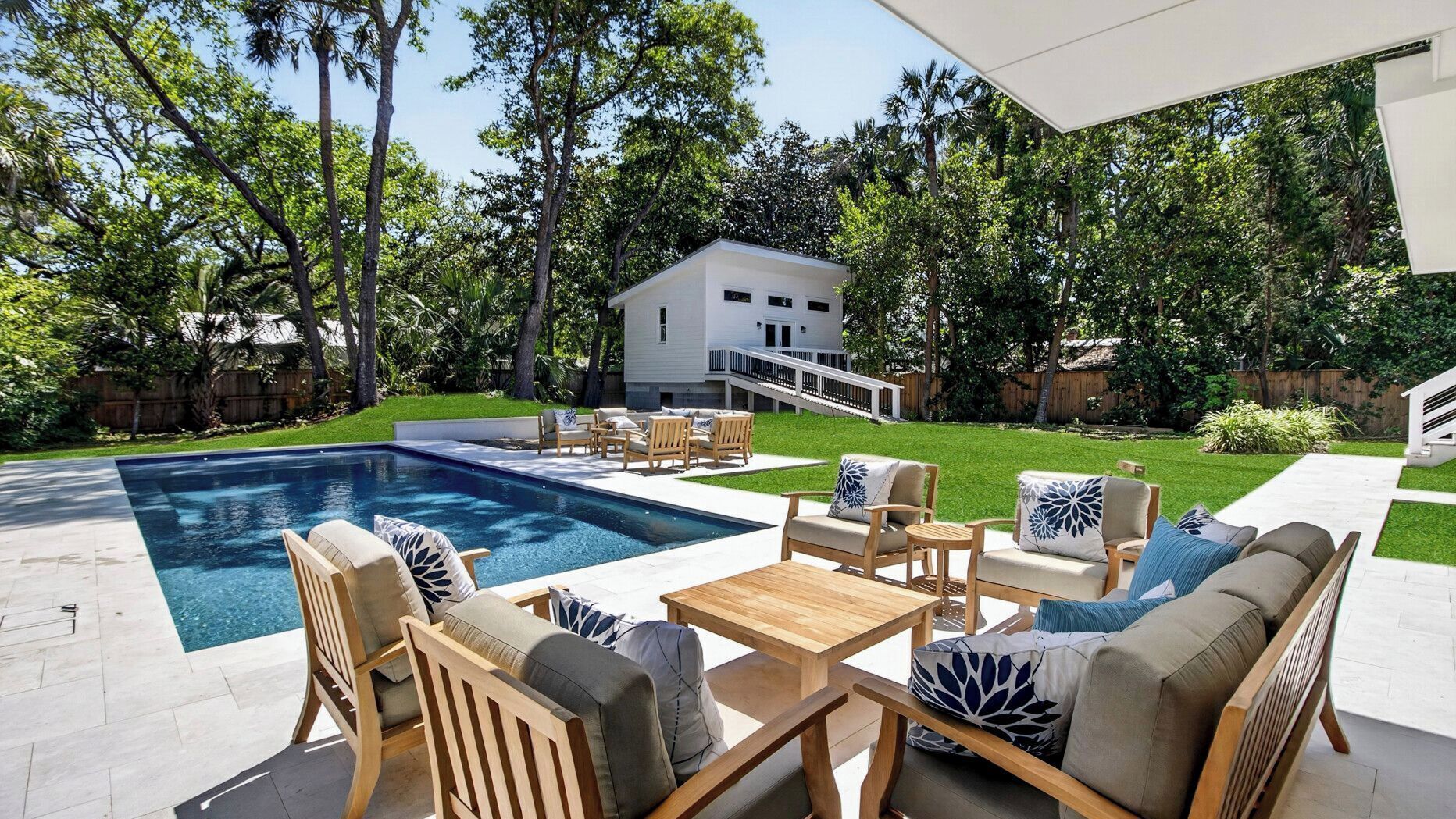 A backyard with a swimming pool, outdoor furniture, and a two-story house.