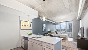 Eine moderne Küche mit Geschirrspüler, Spüle und Essbereich mit großem Fenster und Blick auf die Stadt.