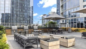 Eine Terrassenanlage im Freien mit Sitzgelegenheiten und Grillplatz, umgeben von modernen Gebäuden.