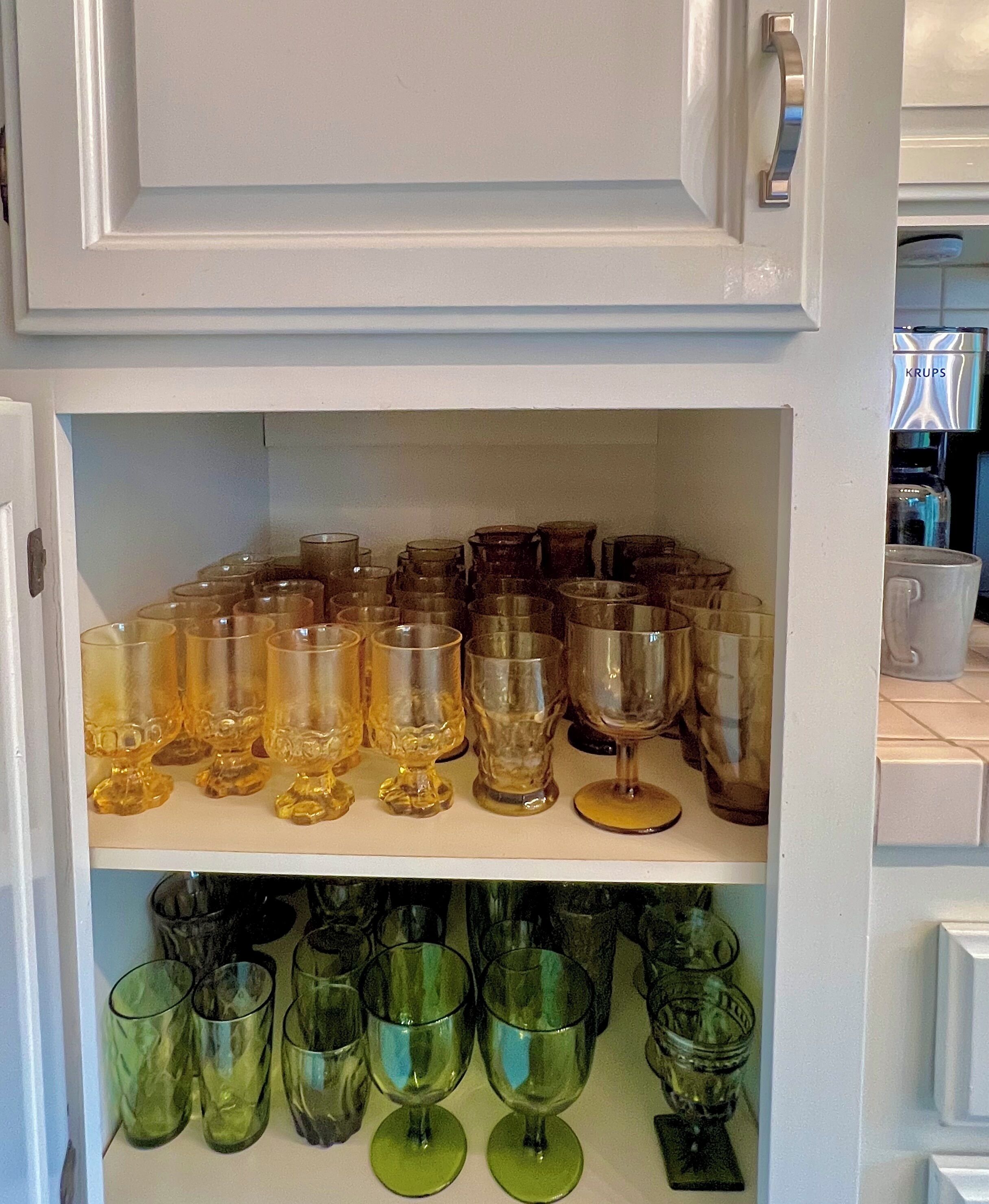 A shelf with various glassware, including wine glasses and tumblers.