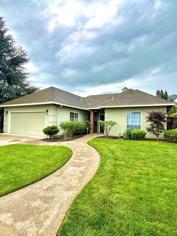 A two-story house with a garage, a driveway, and a well-maintained lawn.