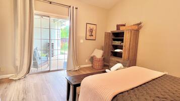 Quarto com cama, guarda-roupa de madeira, janela com cortinas e vista exterior.