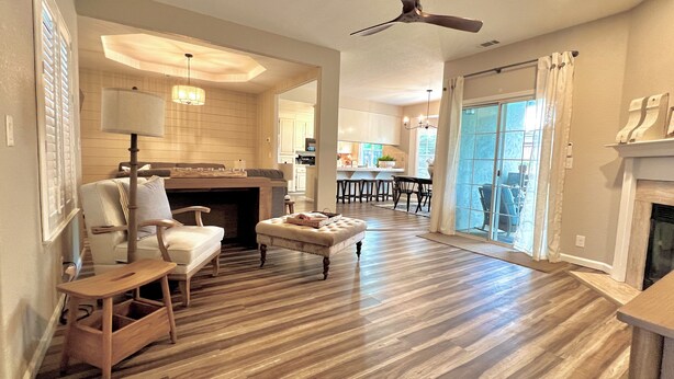 A spacious living room with a fireplace, a ceiling fan, and a view to the dining area. - Vineyard Getaway 3BR Home in Lodi minutes away from shopping & attractions (Lodi)